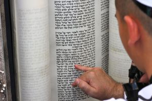 A boy reads the ancient Hebrew text from a Torah scroll at his Bar Mitzvah at the Western Wall holy site in Jerusalem. (Photo: Daniel Estrin)