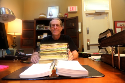 Warren Perrin, an attorney in Lafayette, LA, has a stack of files documenting how The Council for the Defense of French in Louisiana has attempted to stop people from using the term “coonass” in certain instances. Perrin served as president of the state agency for 16 years. (Photo: Veronica Zaragovia)